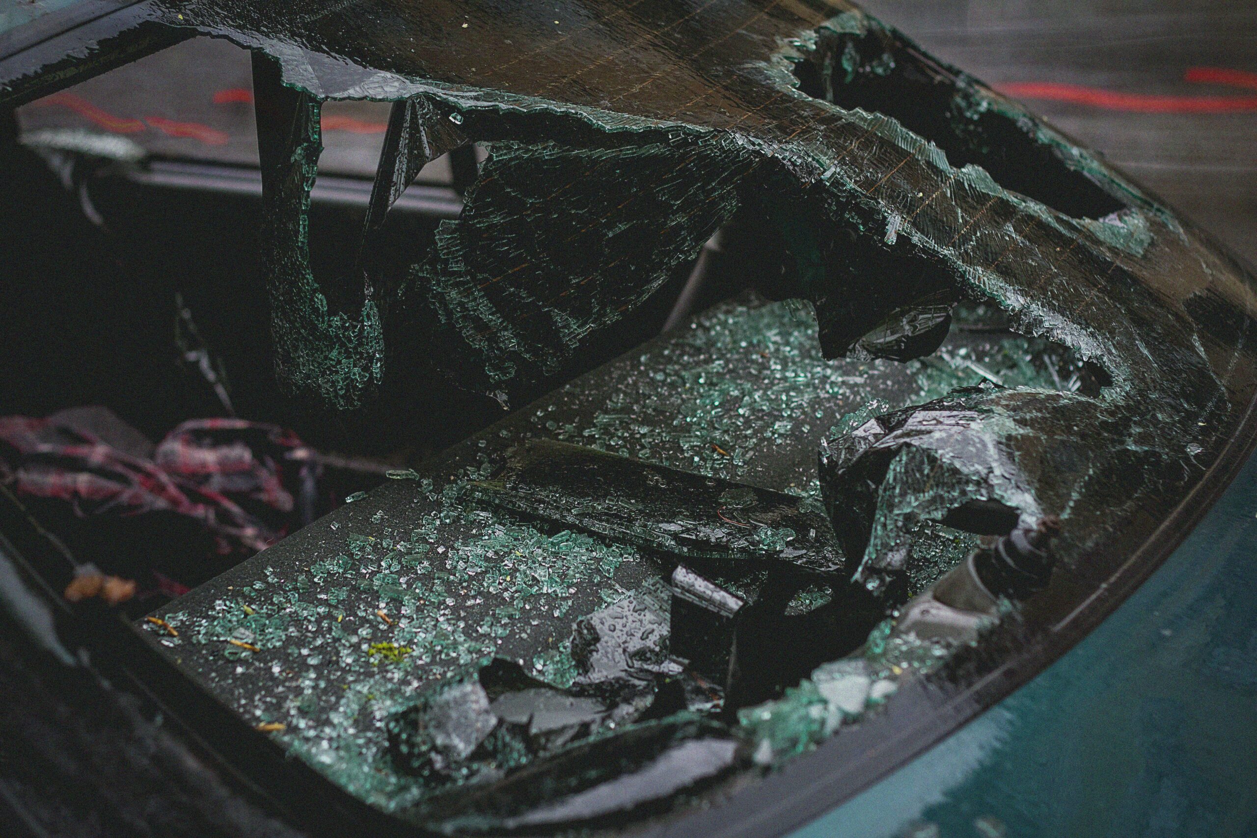 Detailed view of shattered car windshield after accident, emphasizing damage and broken glass.